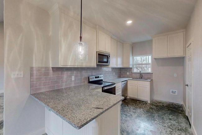 Kitchen with stainless steel appliances, light stone countertops, a sink, and decorative backsplash | Image 11