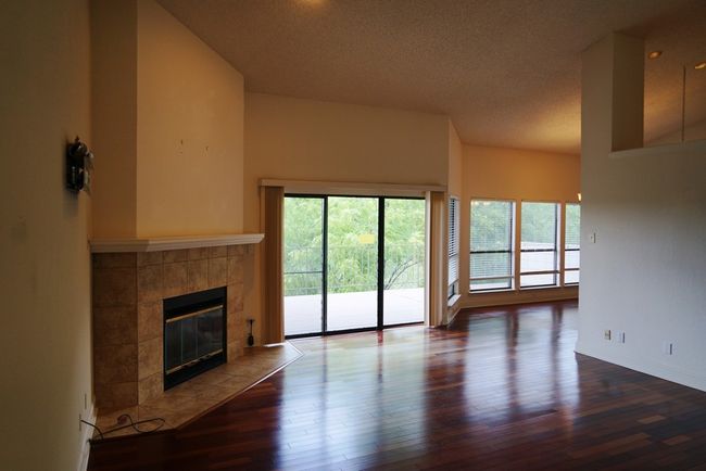 Unfurnished living room featuring a tile fireplace, wood finished floors, a textured ceiling, and baseboards | Image 7