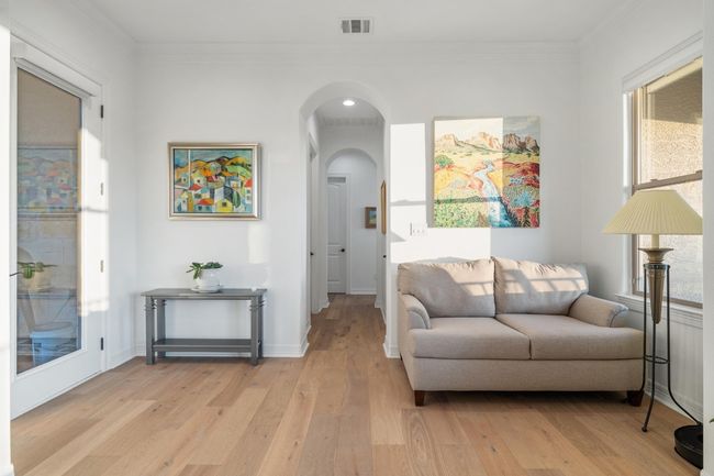 Living room with light wood-style floors, arched walkways, and crown molding | Image 15