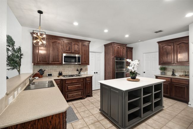 Kitchen featuring tasteful backsplash, open shelves, visible vents, a sink, and stainless steel appliances | Image 11