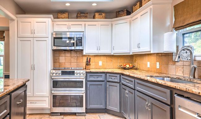 Kitchen with white cabinets, stainless steel appliances, a sink, gray cabinetry, and backsplash | Image 20