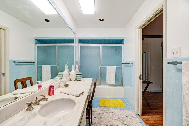 Bathroom featuring vanity, wood finished floors, combined bath / shower with glass door, and tile walls | Image 16