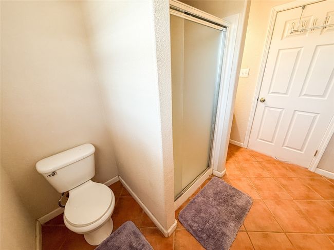 Bathroom featuring tile patterned floors, toilet, a stall shower, and baseboards | Image 15