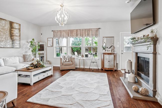 Living area featuring a fireplace with raised hearth, wood finished floors, and a chandelier | Image 13