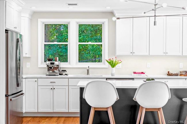 Kitchen featuring freestanding refrigerator, a breakfast bar, light countertops, a sink, and white cabinetry | Image 14