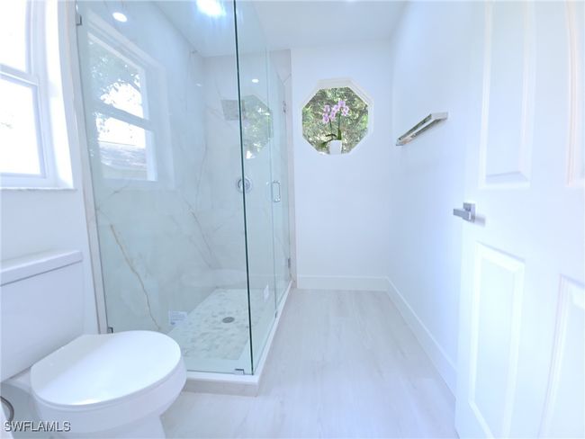 Bathroom with plenty of natural light, a marble finish shower, and toilet | Image 24