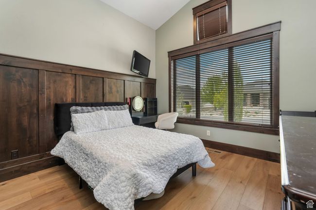 Bedroom with vaulted ceiling, visible vents, light wood finished floors, and baseboards | Image 17
