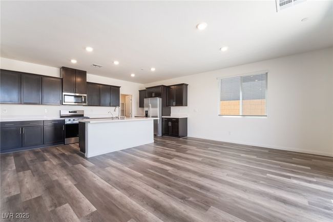 Kitchen with appliances with stainless steel finishes, wood finished floors, light countertops, recessed lighting, and an island with sink | Image 8