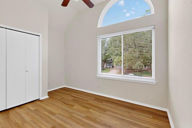 Unfurnished bedroom with multiple windows, light wood-type flooring, baseboards, a closet, and vaulted ceiling | Image 24