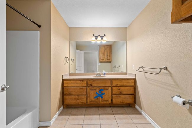 Full bathroom featuring tile patterned flooring, vanity, washtub / shower combination, and a textured wall | Image 14