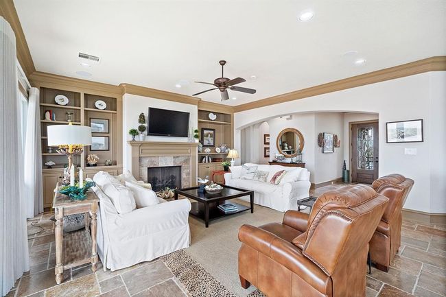 An open concept inviting living area, featuring a cozy fireplace, built-in cabinetry, and water views from every window throughout the home | Image 7