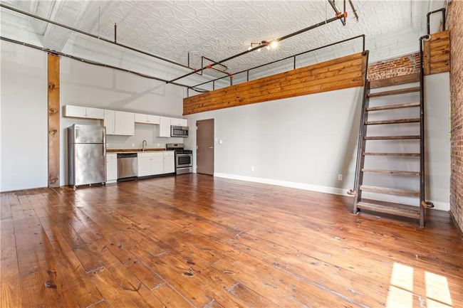 Unfurnished living room featuring a high ceiling and dark wood-style floors | Image 5