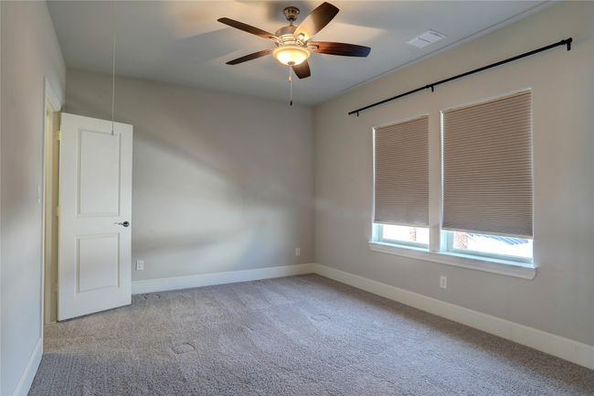 Unfurnished room featuring carpet, a ceiling fan, visible vents, attic access, and baseboards | Image 20
