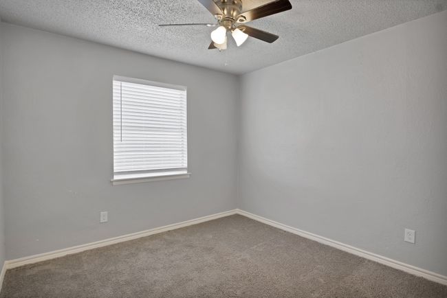 Carpeted empty room with a ceiling fan, baseboards, and a textured ceiling | Image 18