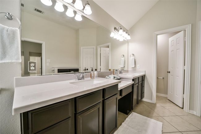 Double sinks and a vanity area give room for everyone to have their own space. Behind the vanity is extra cabinetry offering plenty of storage. | Image 16