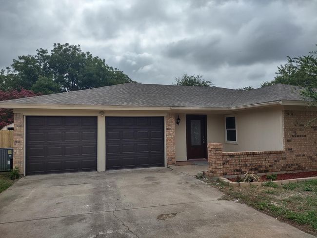 Ranch-style home with brick siding, roof with shingles, driveway, and an attached garage | Image 4