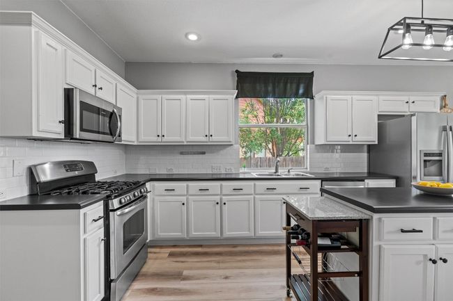 Kitchen featuring stainless steel appliances, dark countertops, white cabinetry, and recessed lighting | Image 10