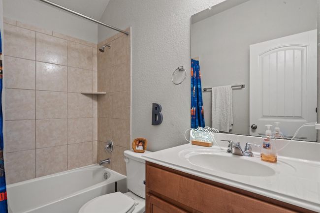 Bathroom with vanity, toilet, a textured wall, and shower / bath combo with shower curtain | Image 27