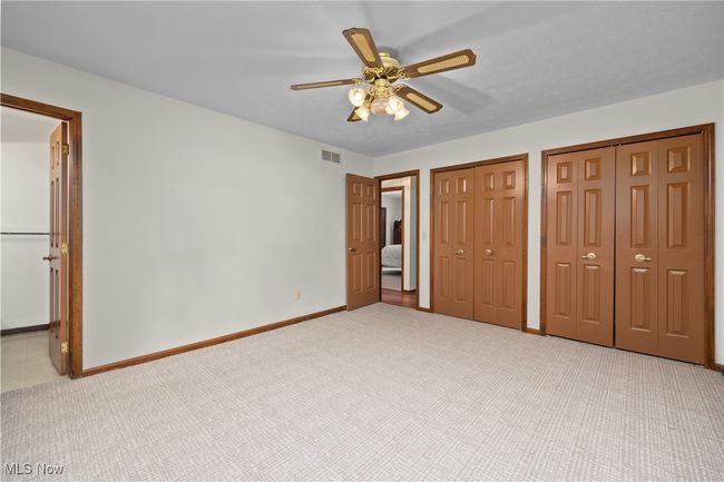 Unfurnished primary bedroom featuring carpet, two closets & ceiling fan | Image 20