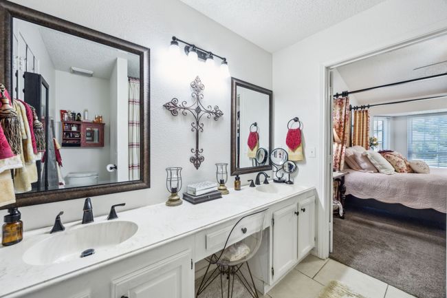 Ensuite bathroom featuring a textured ceiling, double vanity, tile patterned floors, and toilet | Image 22