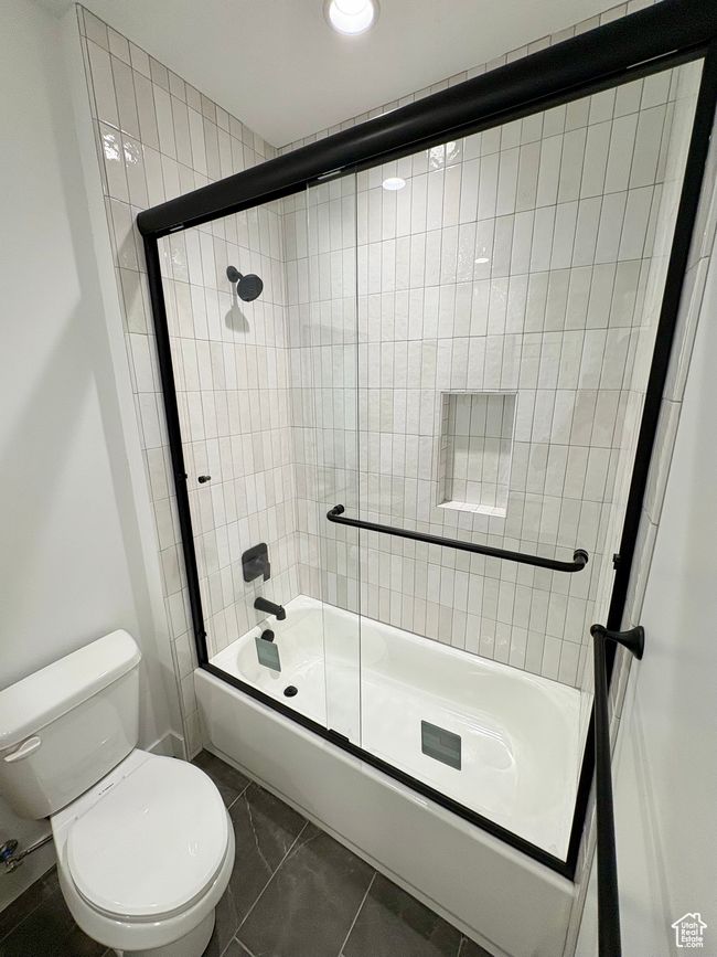 Full bathroom featuring enclosed tub / shower combo and marble look tile flooring | Image 8
