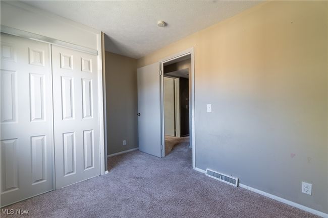 Unfurnished bedroom with carpet flooring, a textured ceiling, baseboards, visible vents, and a closet | Image 16