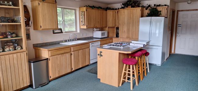 Kitchen featuring a center island, a sink, radiator, carpet, and white appliances | Image 22
