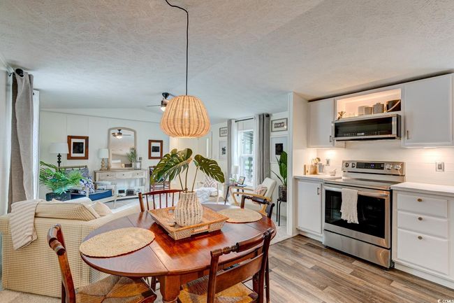 Dining area with light wood-style flooring, a textured ceiling, ceiling fan, and lofted ceiling | Image 10