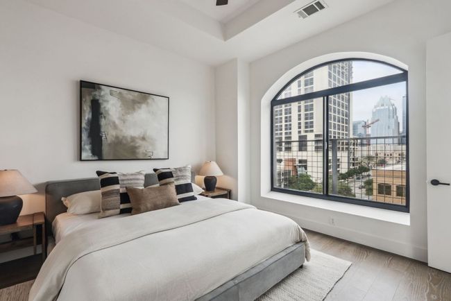 Bedroom featuring visible vents, baseboards, wood finished floors, and a city view | Image 10