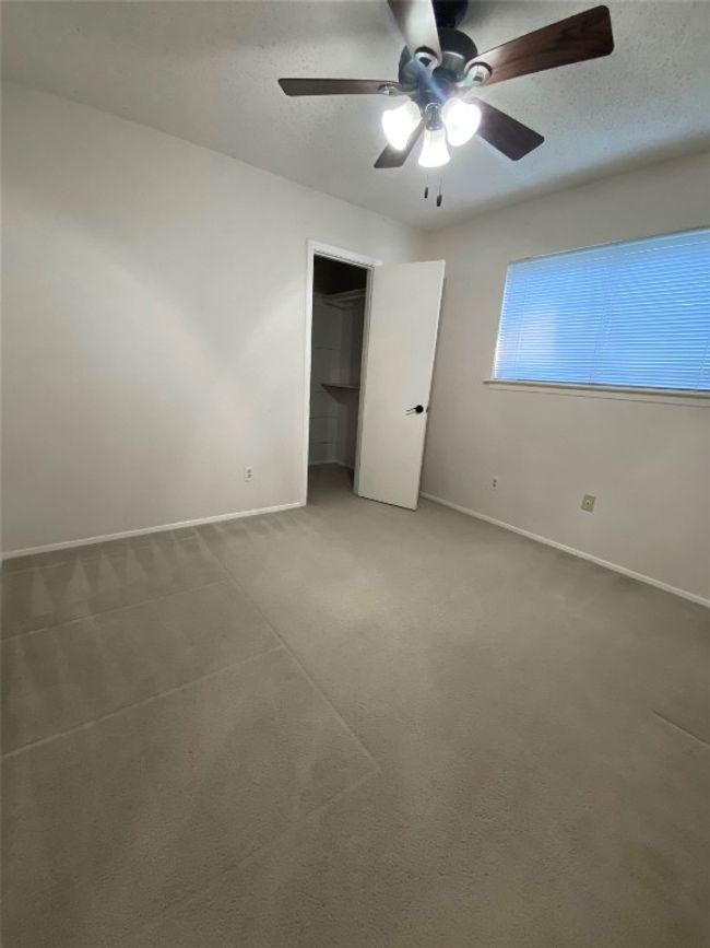 Unfurnished bedroom with a ceiling fan, baseboards, carpet, and a closet | Image 23