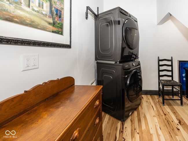 laundry room featuring stacked washing machine and dryer and light wood-style floors | Image 28