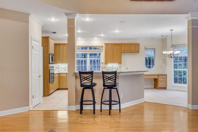 Kitchen featuring decorative backsplash, a breakfast bar, appliances with stainless steel finishes, light wood-type flooring, and ornamental molding | Image 14