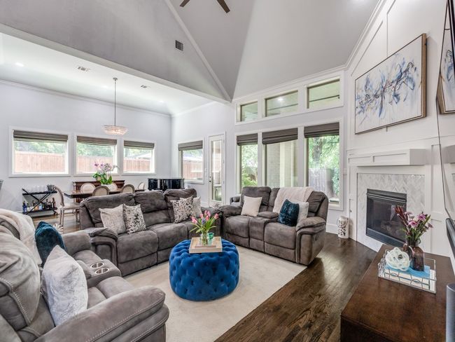 Living room featuring wood finished floors, high vaulted ceiling, healthy amount of natural light, a ceiling fan, and a tile fireplace | Image 10
