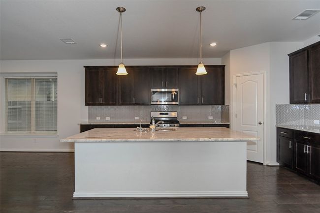 Kitchen featuring dark brown cabinetry, a sink, light stone countertops, stainless steel appliances, and visible vents | Image 11