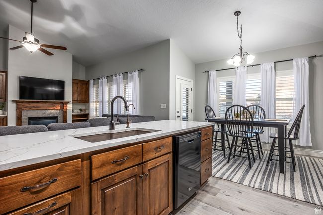 Kitchen featuring vaulted ceiling, a wealth of natural light, dishwasher, sink, and light stone counters | Image 7