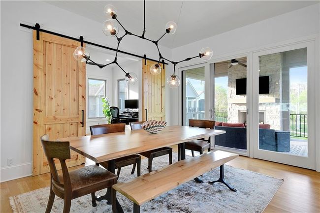 Dining area with light wood finished floors, a stone fireplace, ceiling fan, and a barn door | Image 29