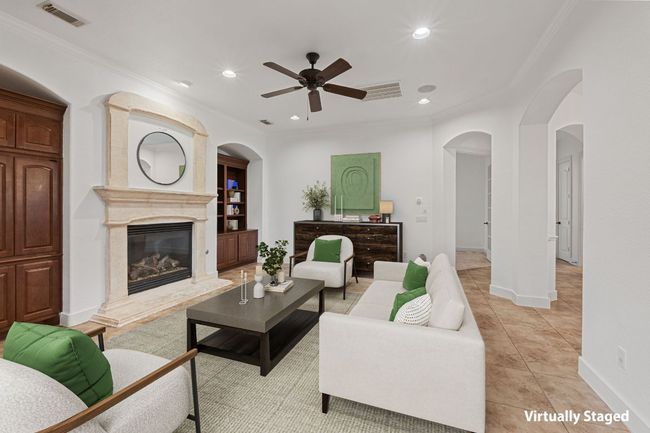 Living room featuring a ceiling fan, arched walkways, recessed lighting, a high end fireplace, and ornamental molding | Image 10