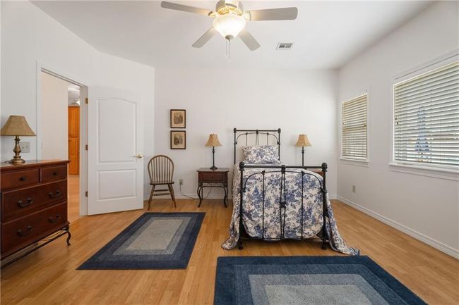 Bedroom featuring light wood-style flooring, baseboards, a ceiling fan, and visible vents | Image 18