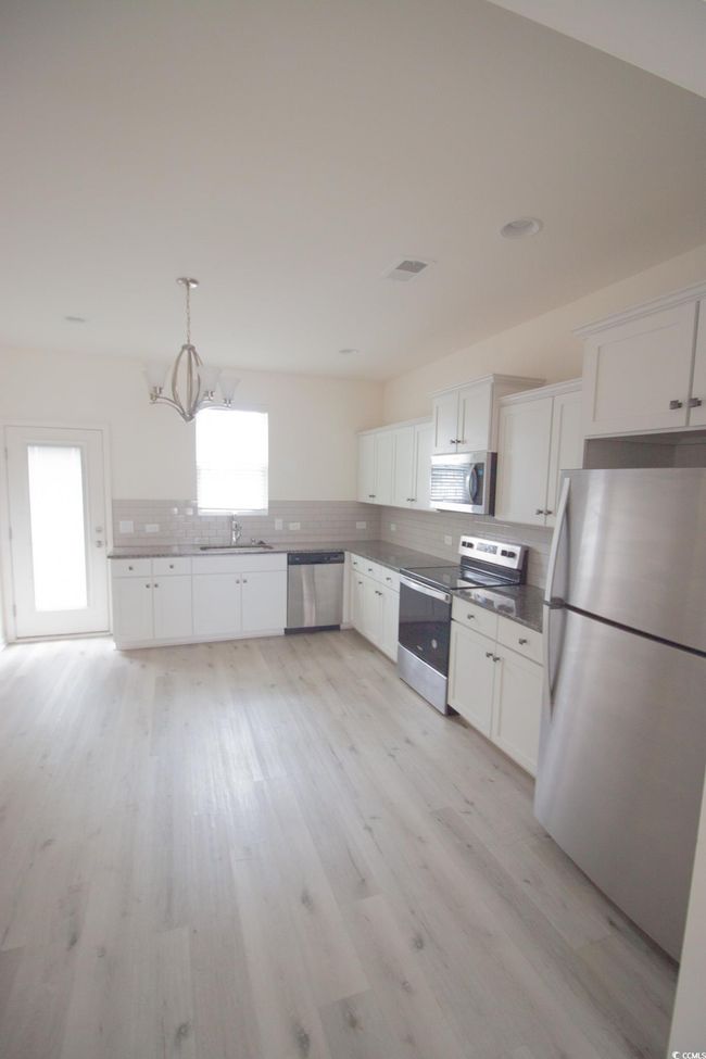 Kitchen with stainless steel appliances, a sink, tasteful backsplash, and white cabinetry | Image 4