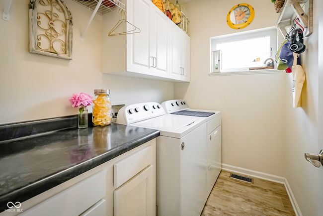 laundry room with washer and clothes dryer, wood finished floors, cabinet space, and baseboards | Image 22
