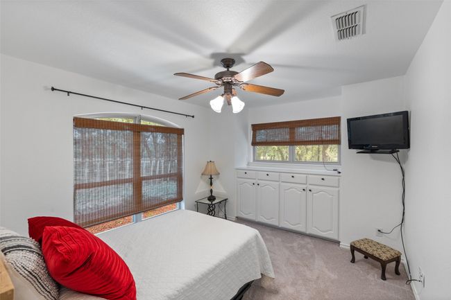 Bedroom featuring a ceiling fan, light colored carpet, multiple windows, and visible vents | Image 17