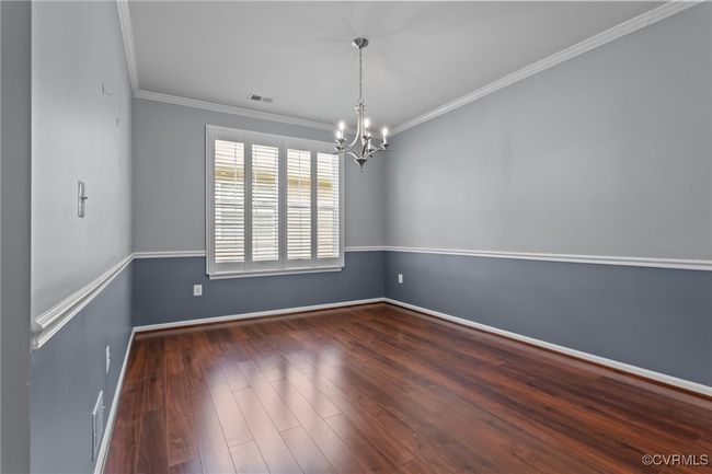 Spare room featuring a chandelier, ornamental molding, and wood finished floors | Image 13