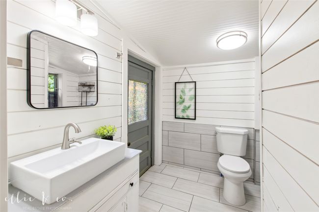 Main Bathroom featuring toilet, vanity, tile patterned flooring, and ship lap walls | Image 23