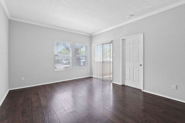 Unfurnished bedroom with crown molding, a textured ceiling, and wood finished floors | Image 4