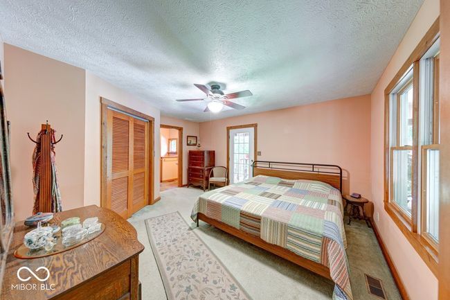bedroom featuring light colored carpet, a closet, a textured ceiling, and a ceiling fan | Image 27