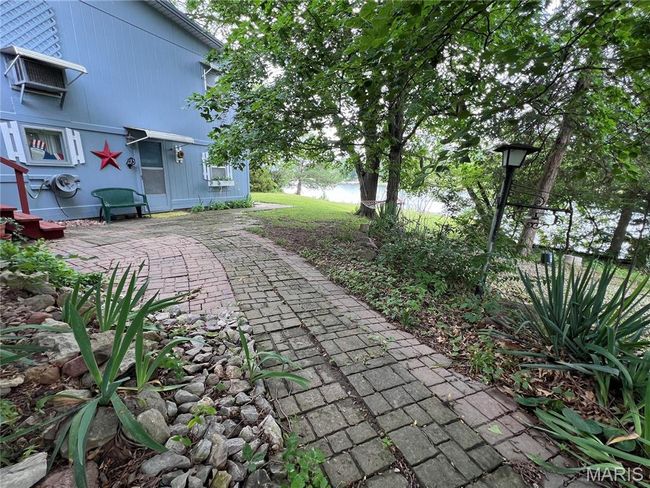 View of home's exterior with metal roof, a lawn, a wall mounted AC, and fence | Image 4
