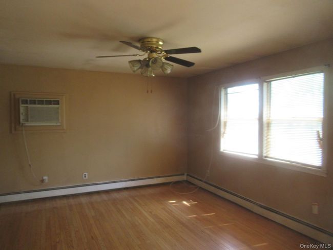Spare room with an AC wall unit, a ceiling fan, healthy amount of natural light, and light wood-style floors | Image 8