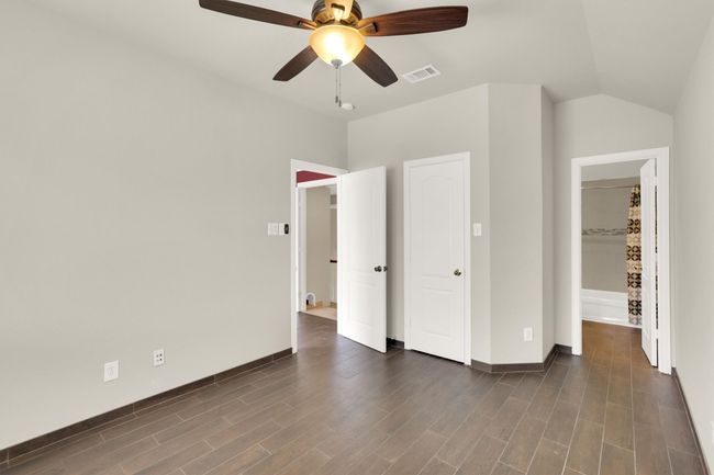 Unfurnished bedroom featuring dark wood-type flooring, visible vents, baseboards, and ceiling fan | Image 25
