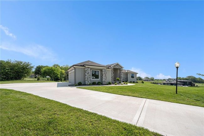 View of front of home with a front yard, stone siding, and an attached garage | Image 6