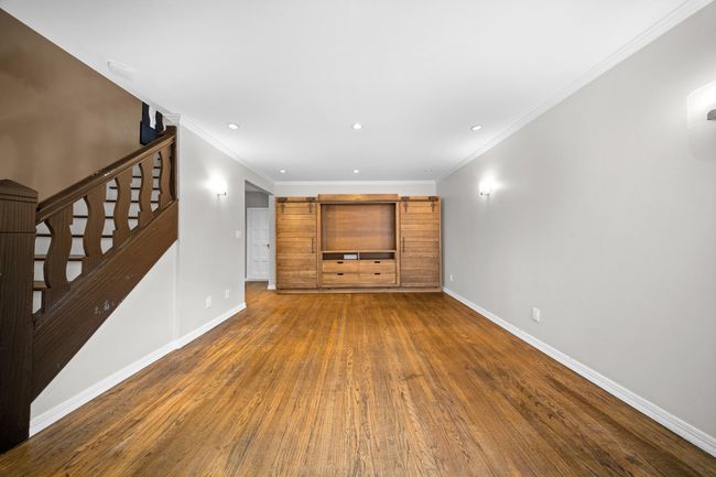 Unfurnished living room featuring baseboards, wood finished floors, stairs, recessed lighting, and crown molding | Image 17